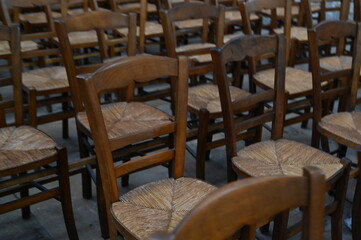 Rows of wooden chairs in an old church or hall. Vintage seating arrangement with warm wood tones and classic atmosphere, symbol of tradition, community, and history.