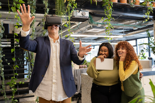 Businessman wearing vr headset interacting with colleagues in coworking space