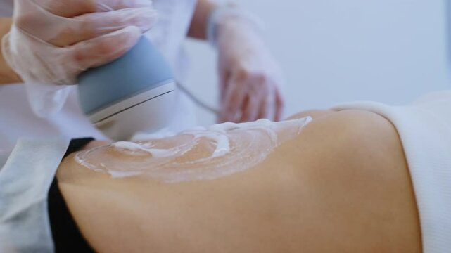 Anonymous Masseur Smears Cream on Clients Stomach with Modern Massage Device