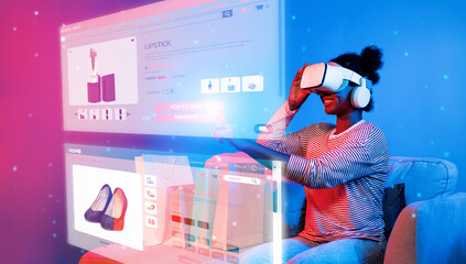African girl looking list while wearing VR glass and sitting at sofa with shopping bag. Teenager using augmented reality glasses while choosing and buying product at neon color background. Ingenuity.