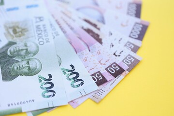 Mexican pesos money bills in big amount lies on yellow color table close up