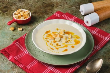 Cauliflower puree soup with white bread croutons and aromatic butter as a garnish in a light...