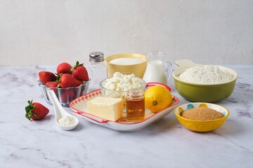 Prepared ingredients for making eggless curd cake with strawberries on a light marble background. Pastries with strawberries.