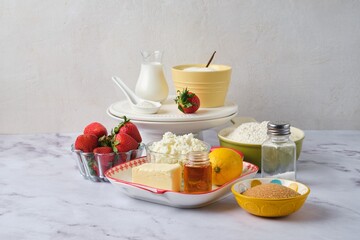 Prepared ingredients for making eggless curd cake with strawberries on a light marble background. Pastries with strawberries.