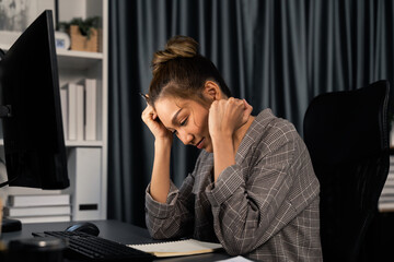 Businesswoman working on computer with stretching arm up and down manner with body health ache of strain overwork unfinished project job on website at late over night time at modern office. Infobahn.