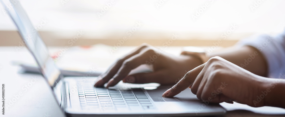 Poster Closeup of unrecognizable black female working on laptop, typing on computer keyboard while working in office, side view, cropped image