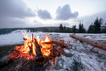 Ognisko w zimowym, górskim krajobrazie. Śnieg, las i chmurne niebo © Adam.rtk