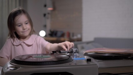 Young girl is carefully placing the needle on a vinyl record player, enjoying a nostalgic music experience in a cozy home setting
