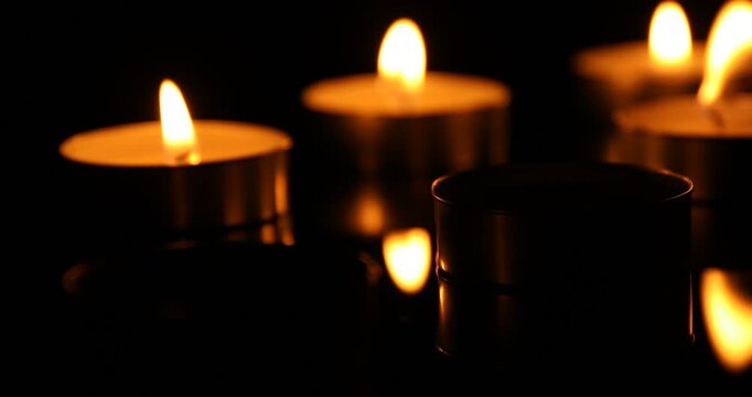 Woman lightening candles with match in darkness, closeup