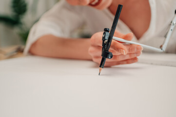 Architect drawing circle on blueprint with compass in the office
