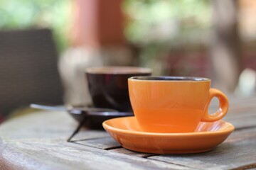 Two cups of coffee stand on a table outside, breakfast, morning coffee. Ceramic cups orange color