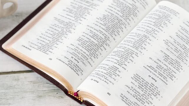 Open holy bible book with cup of coffee on wooden table. Christian Scripture study in the morning, biblical concept.