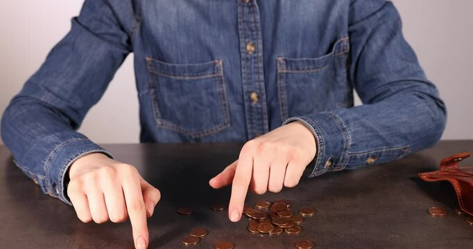 Woman counting coins at grey table, closeup. Financial problems