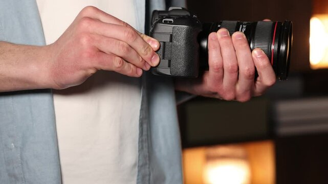 Man inserting SD memory card into photo camera indoors, closeup
