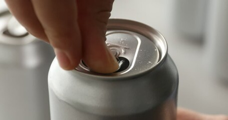 Woman opening can of refreshing drink on blurred background, closeup