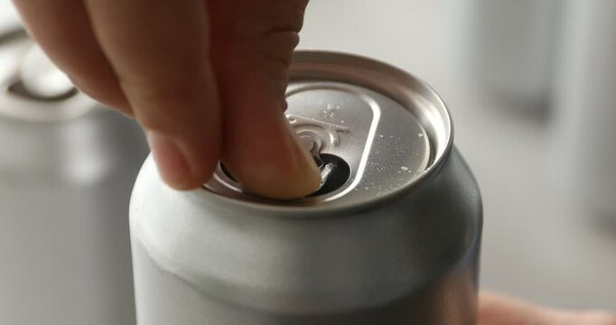 Woman opening can of refreshing drink on blurred background, closeup