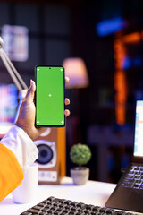 Young woman scrolling on green screen mobile phone, checking social media feed. Self employed person surfing the internet from chroma key smartphone device in apartment, close up
