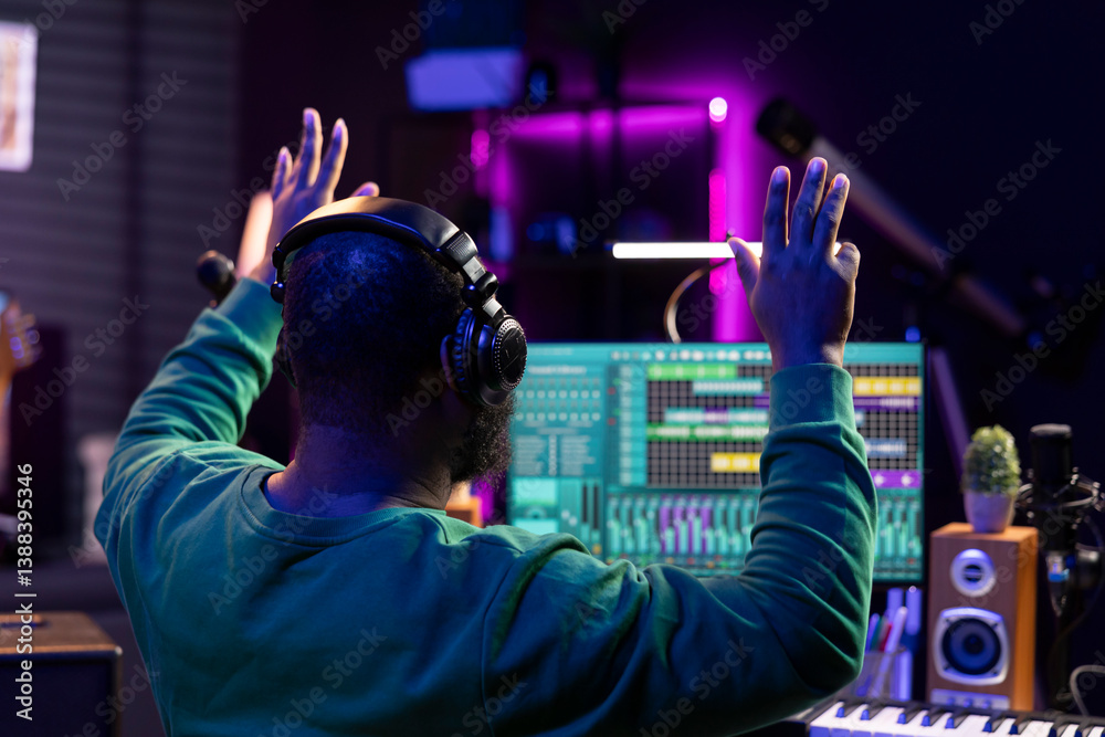 Poster African american sound designer counting down before he starts the recording session, working with mixing console and software for editing in post production. Producer making music in home studio.