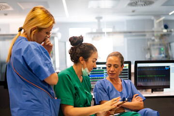 Medical team analyzing data on tablet in hospital control room