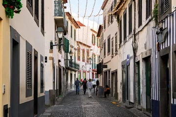 Selbstklebende Fototapeten Enge Straßen Pedestrians walk along the narrow cobblestone streets at  the Rua de Santa Maria in the touristic center of the old town of Funchal, Madeira Island Portugal.  © Kirk Fisher