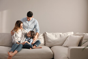 Family with little daughter resting on sofa in living room