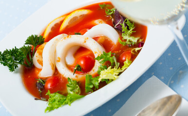 Beautifully served bowl with tomato soup with squid and greens
