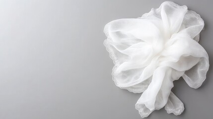 Fototapeta premium A crumpled white silk scarf rests on a gray background. The scarf is lightweight and sheer, with delicate edges. The image is high-quality, well-lit, and features a simple composition. The style is