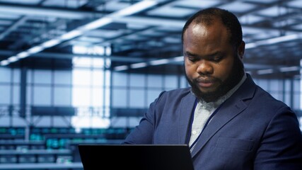 Software developer in data center runs diagnostic tests and error checking utilities on laptop to...