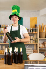 Man seller in traditional Irish green cap offers Irish ale on St. Patrick Day in supermarket