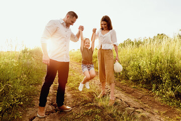 Fototapeta premium Upbringing. Lovely parents spending time with their child who is jumping up on the road