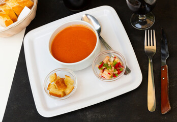 Delicious Andalusian gazpacho, vegetable soup puree traditionally served cold with crispy croutons and diced fresh bell pepper and cucumber. Spanish cuisine