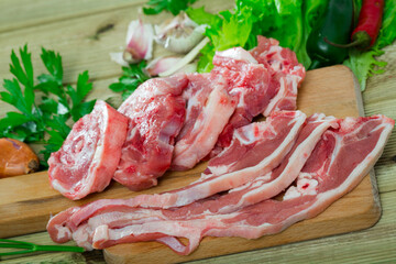 Fresh slices of mutton and vegetables assortment on natural wooden desk, top view