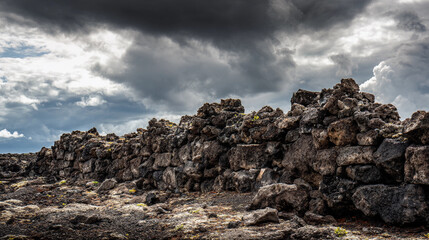 Fototapeta premium Immerse Yourself in the Raw Power of a Dramatic Volcanic Stone Wall by the Lava Flow, Embracing Nature's Fierce Energy and Striking Geologic Sculptural Artistry