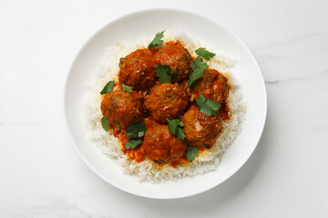 Delicious meatballs with rice, sauce and parsley on white marble table, top view