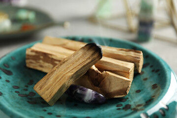 Smoldering palo santo stick and gemstone on table, closeup