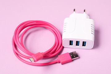 USB power adapter and charge cable on pink background, closeup
