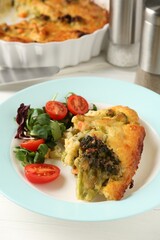 Tasty vegetable casserole and salad on white wooden table, closeup