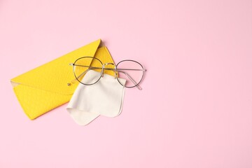 Case with stylish glasses and cleaning cloth on light pink background, top view. Space for text