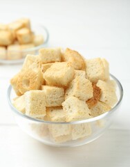Delicious crispy croutons on white wooden table, closeup. Space for text