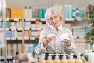 Mature woman shopper buys box of pills in pharmacy