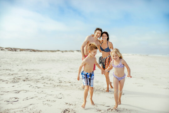 Happy young family on a sandy beach on their summer vacation - Powered by Adobe