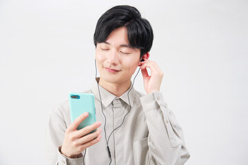 イヤホンをつけて音楽を聴く20代男性　白背景