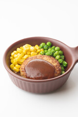 コーンとグリーンピースの添えられた器に盛られたデミグラスソースのハンバーグの単品写真