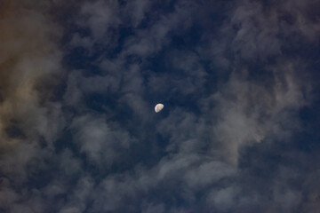 The moon in the dark blue sky with clouds. The lunar eclipse.