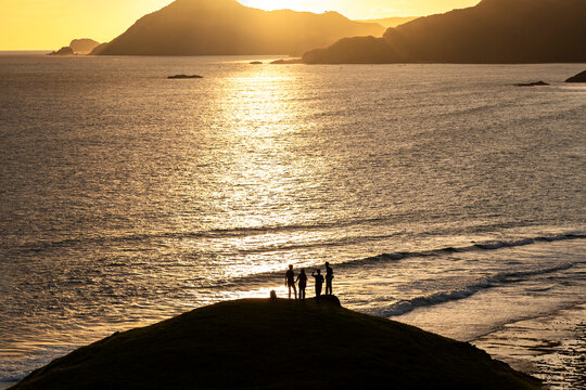 Travelling friends taking photos on seaside hill at sunset, Lombok, Indonesia