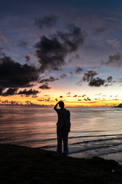 Female traveler gazing at sunset over sea, Bukit Merese, Lombok, Indonesia