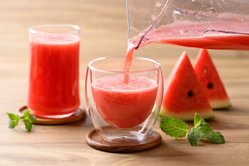 Fresh watermelon juice pouring in glass on wooden background, Summer drink