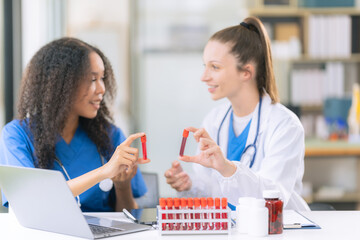 Two female scientists examine liquids in test tubes in a modern laboratory, handling chemicals and...