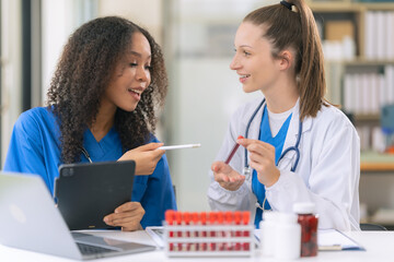 Two female scientists examine liquids in test tubes in a modern laboratory, handling chemicals and...