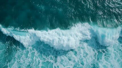 Obraz premium Aerial view of turquoise ocean waves crashing, showcasing dynamic textures and vibrant colors of water.